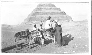 Photograph of a female tourist on a donkey being led towards a pyramid, Egypt 1925